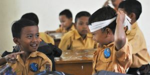 children in school classroom, one wearing a bandana like a superhero