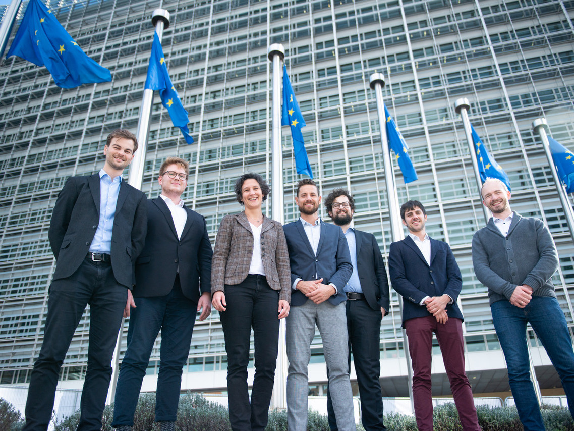 A group of people in front of European flags and an office block