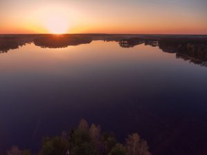 beautiful sunrise over woods and islands of lake, aerial view over trees tops